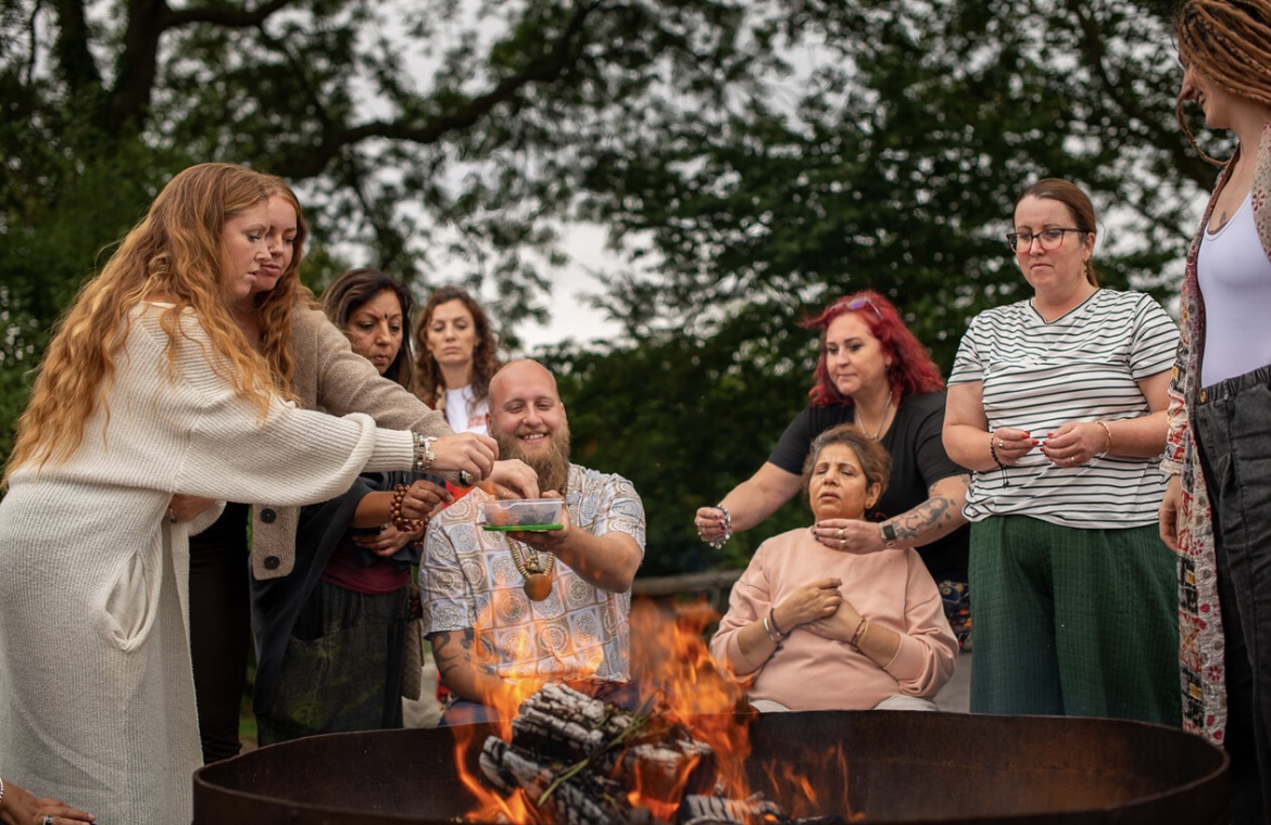 Group gathered around an outdoor fire ceremony among trees