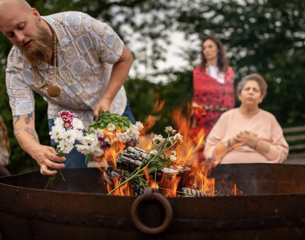 Ceremonial fire offering with flowers at an outdoor gathering