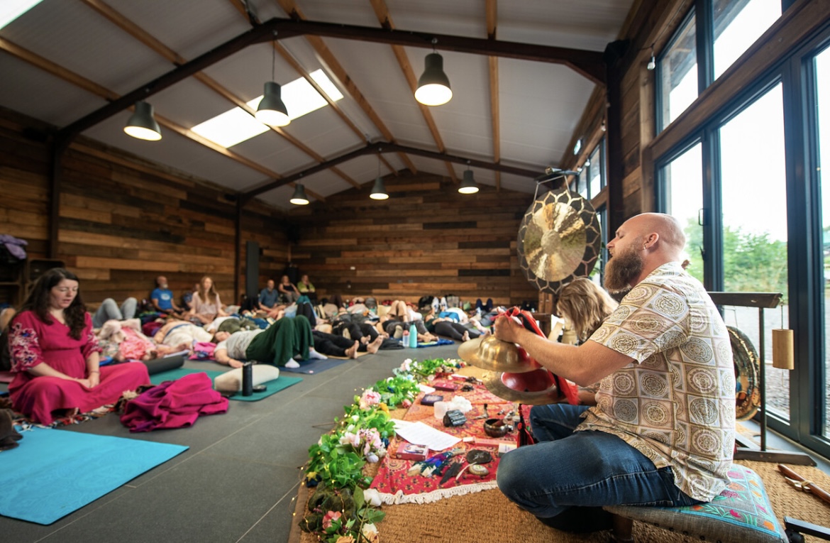 Sound healing session in a wood-panelled studio with participants resting on mats